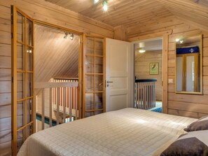 A wooden room with a bed, a door leading to a balcony, and a mirror on the wall. - Weekend lux by Interhome (Sotkamo)