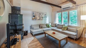 Una sala de estar moderna con chimenea, un conjunto de sofás, una mesa de centro y ventanas amplias.