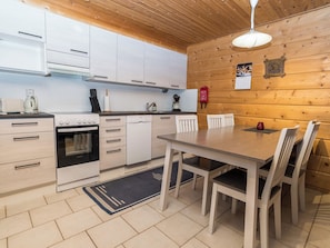 A modern kitchen with white cabinets, a built-in oven, and a dining area with a wooden table and chairs.