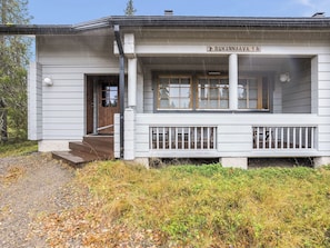 A white building with a porch, a wooden door, and a sign reading 'RUKANNAAVA 1A'. - Rukannaava 1a (2) by Interhome (Kuusamo)