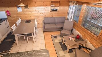 A cozy cabin interior with a dining area, sofa, and a window with blinds.