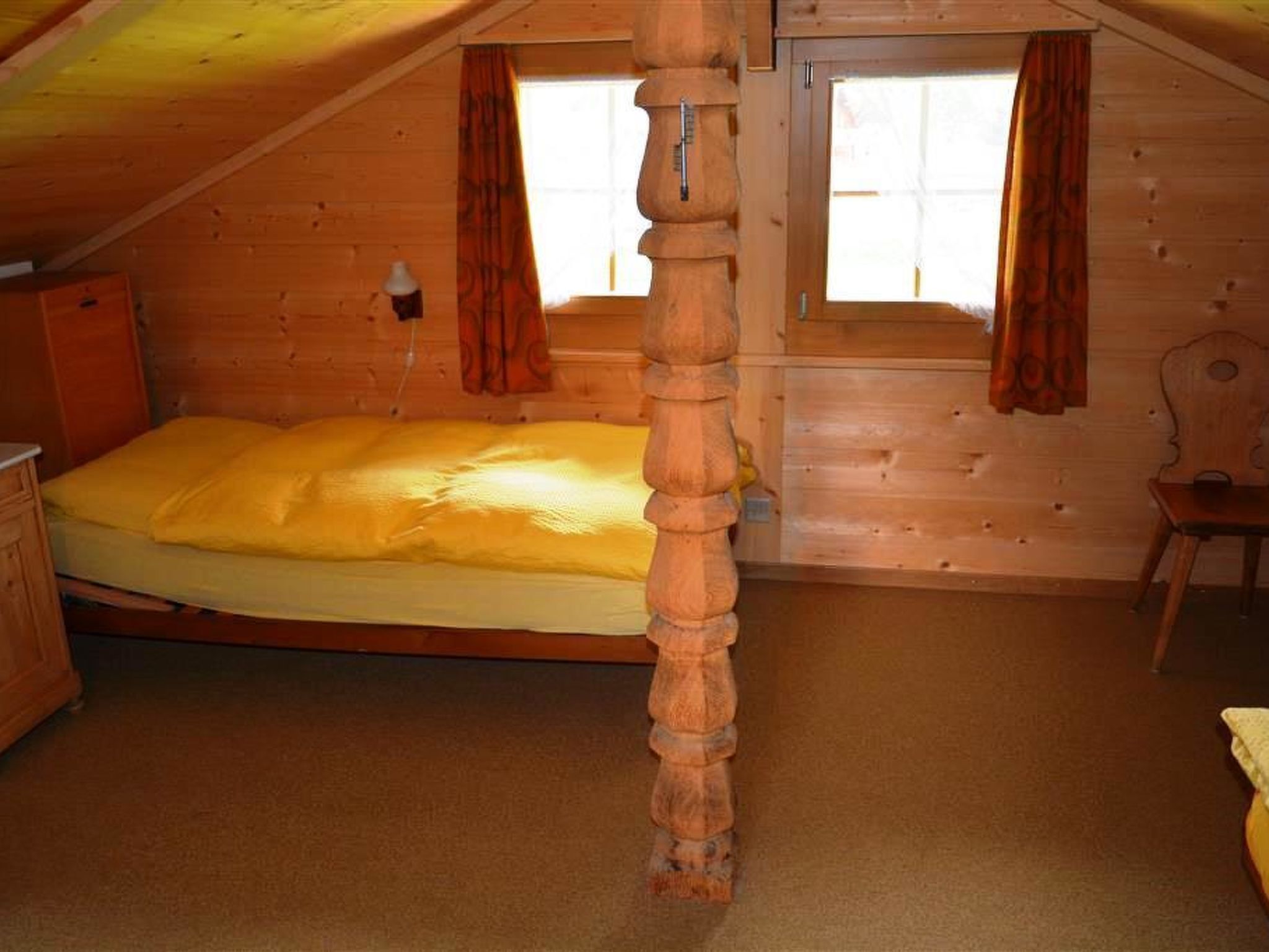 Ett sovrum i en stuga, inrett med en säng, en byrå och en stol.