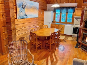 A wooden cabin interior with a dining table, chairs, a fireplace, and a kitchen area. - Vuonkuma by Interhome (Äkäslompolo)