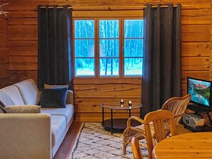 En hyggelig hytteinteriør med en sofa, et lille bord og et fjernsyn.
