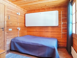 A compact room with a bed, wooden walls, a window, and a whiteboard.