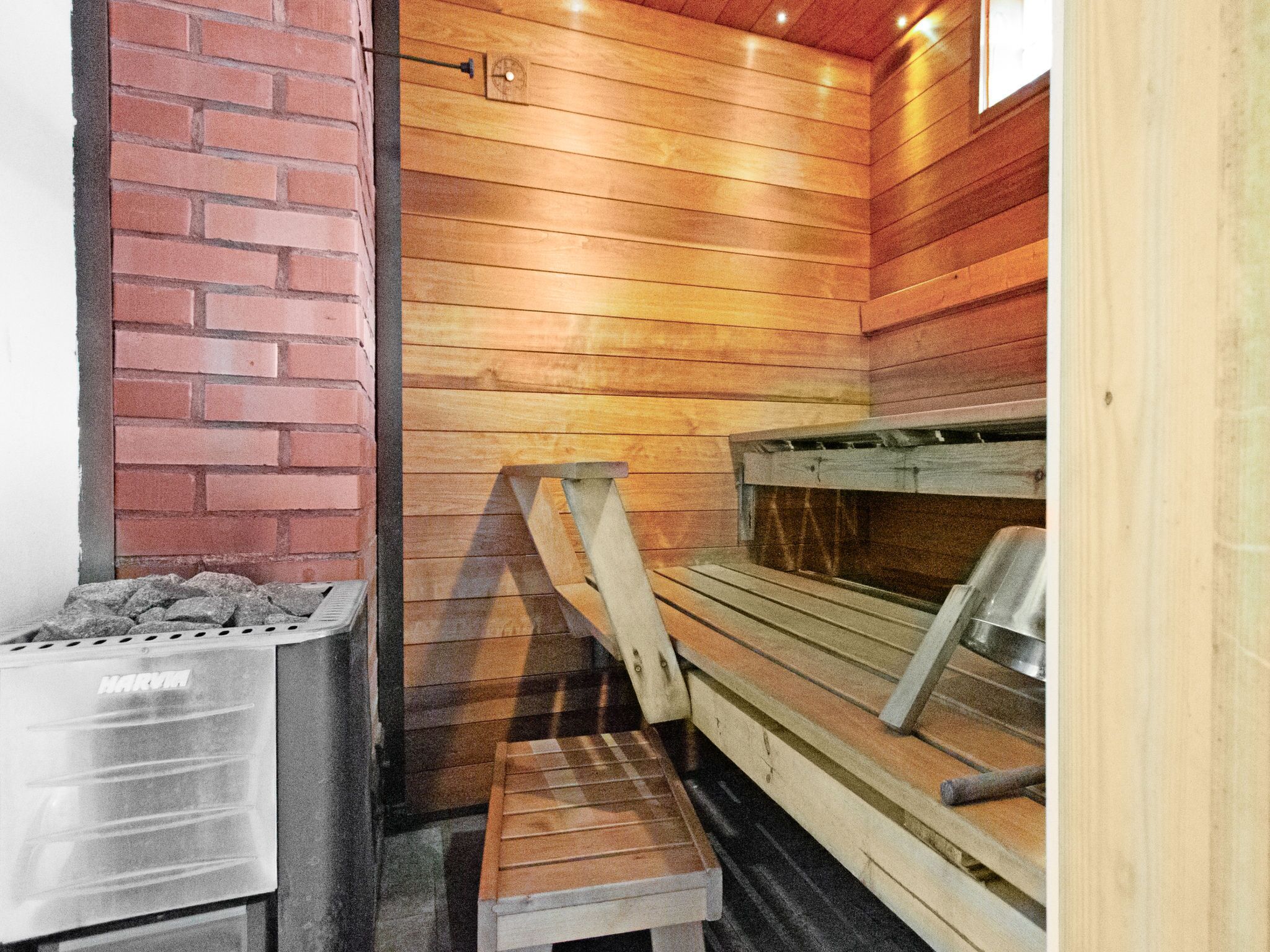 A sauna room with wooden walls, a bench, and a stone container.