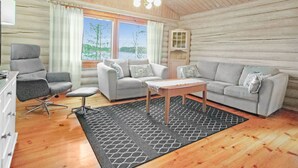 L’intérieur d’un chalet confortable, avec un canapé, un fauteuil et une table à manger.