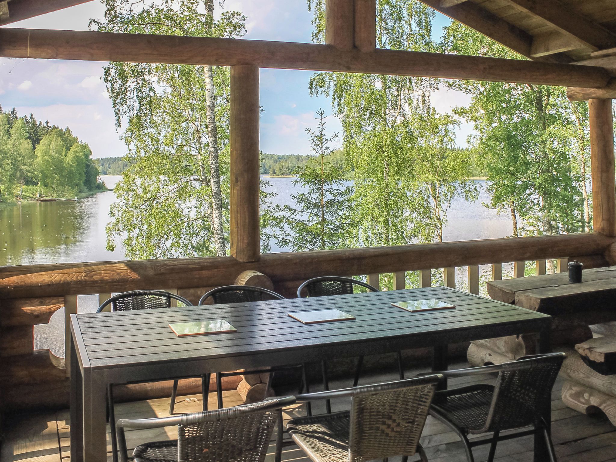 En träveranda med ett bord och stolar med utsikt över en sjö.