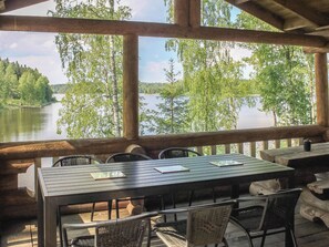Une terrasse en bois avec une table et des chaises donnant sur un lac.