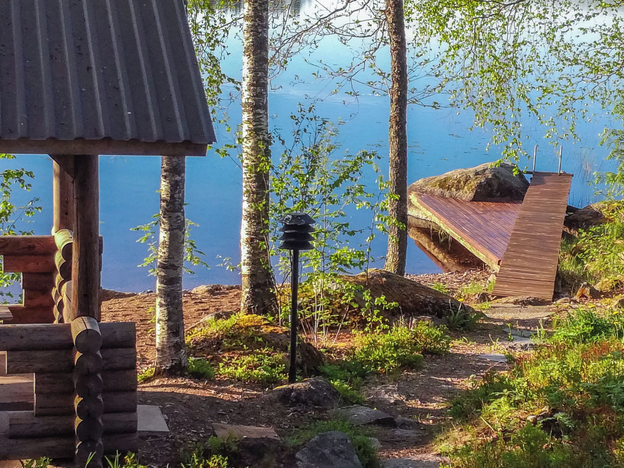 A rustic cabin with a wooden deck overlooking a lake.