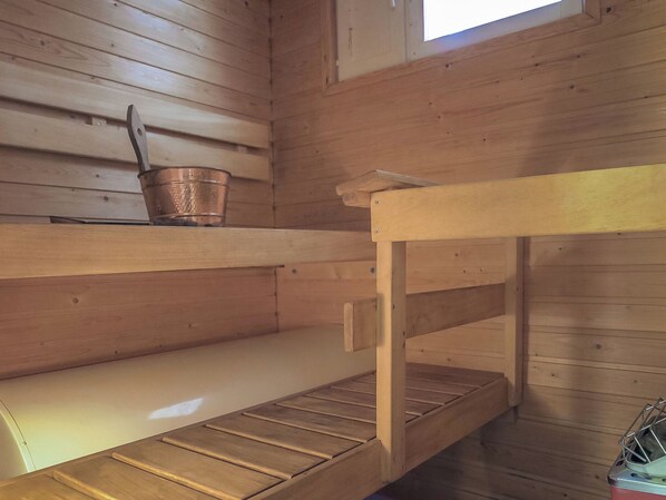A wooden bunk bed with a metal bucket on the top bunk.