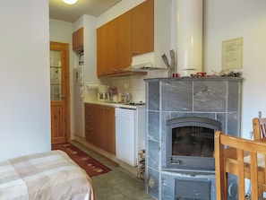 Una cocina compacta con armarios de madera, estufa integrada y un refrigerador pequeño.