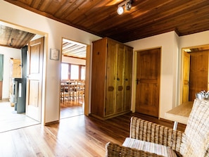 Ein Zimmer mit Holzboden, einer Essecke mit Stühlen und einem Tisch sowie einem großen Kleiderschrank.