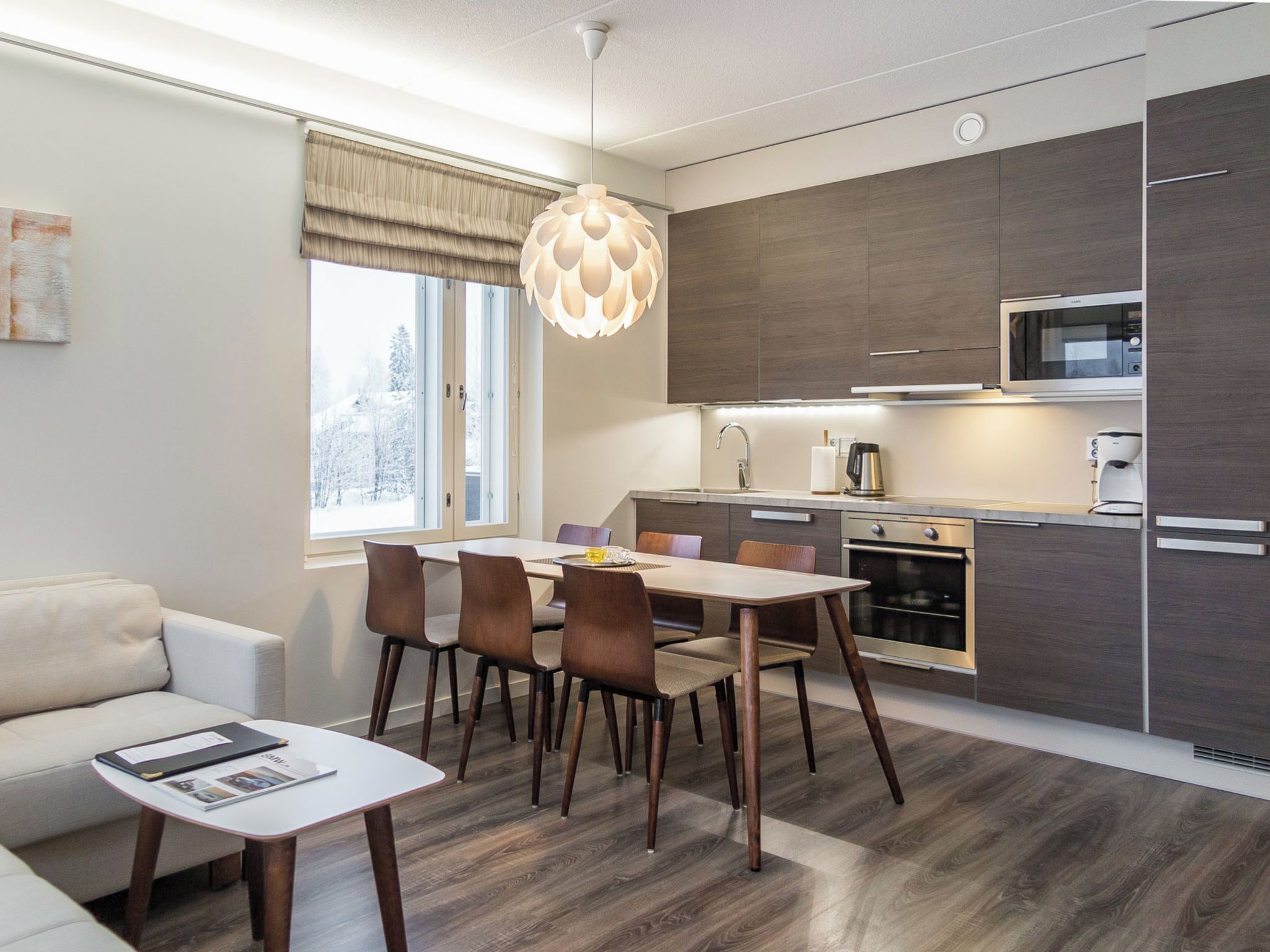 A modern kitchen with a dining area, a sofa, and a coffee table.