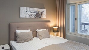 Un letto rifatto con copriletto trapuntato, una lampada da comodino e un comodino con un telecomando.