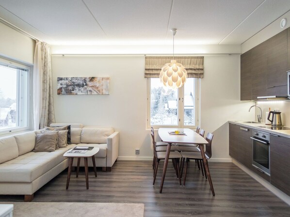 A modern living room with a sofa, dining table, and kitchen area.