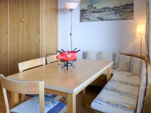 A dining area with a wooden table, chairs, a red pot, and a sofa with patterned cushions. - Beaulieu by Interhome (Zermatt)