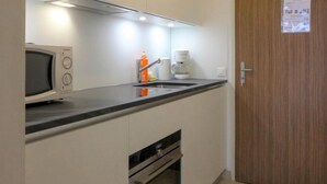 A compact kitchenette with a microwave, coffee maker, and a small oven.