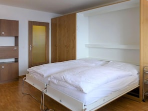 A modern bedroom with a single bed, wooden wardrobe, and a small desk. - Beaulieu by Interhome (Zermatt)