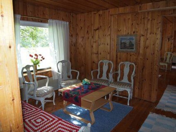 A wooden-paneled room with a table and four white chairs.