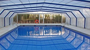 Ein Innenpool mit klarem, blauem Wasser, umgeben von Glaswänden und einem geometrischen Deckenmuster.