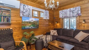 A cozy cabin interior with a sofa, armchair, and a painting of a mountain lake. - Sallanrinne b by Interhome (Salla)