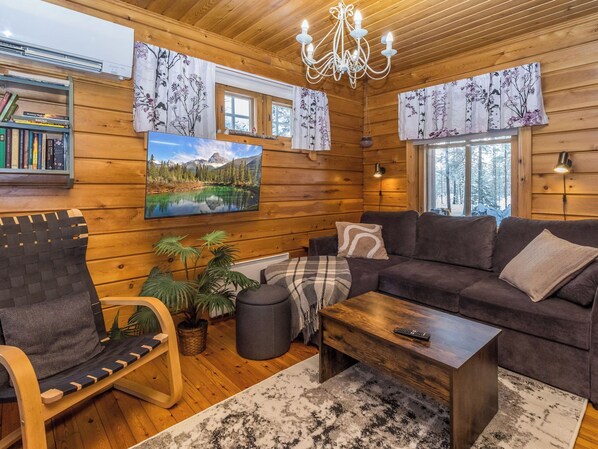 Un interior de cabaña acogedor con un sofá, un sillón y un cuadro de un lago de montaña.