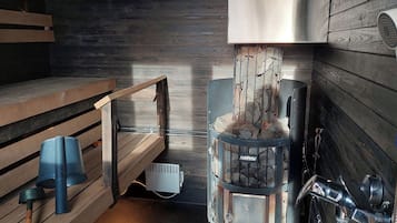 A sauna room with a stone wall, a bench, and a sauna heater labeled 'HARVIA'.