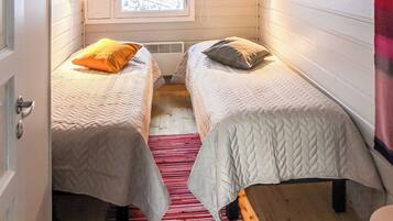 A small, cozy room with two beds, a window with a view, and a red striped rug.