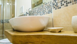 A bathroom with a large white basin on a wooden countertop, a small stone bowl, and a tiled backsplash. - Villa Cristina (Alezio)