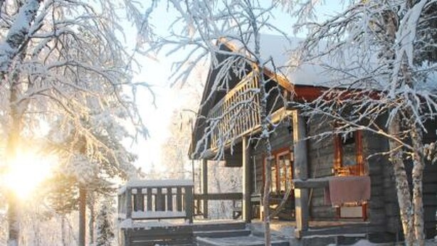 A wooden cabin with a porch and steps leading up to the entrance, surrounded by snow-covered trees. - Vacation home Hilla by Interhome (Kittilä)