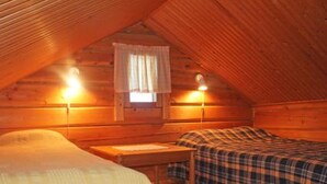 A cozy attic bedroom with two beds, wooden walls, and a sloped ceiling. - Vacation home Hilla by Interhome (Kittilä)