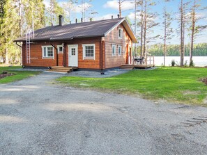 A cabin with a gravel driveway, a wooden deck, and a lake view. - Nesterin helmi by Interhome (Eno)