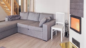 A modern living room with a grey sectional sofa, a white chair, a fireplace, and a staircase.