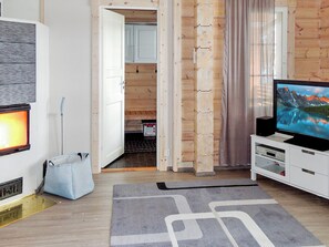 A modern living room with a flat-screen TV, a grey rug, and a wooden door leading to a kitchen. - Nesterin helmi by Interhome (Eno)