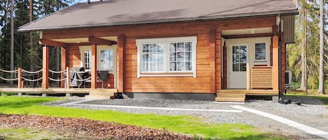 Una cabaña de madera con porche, ventana y puerta.