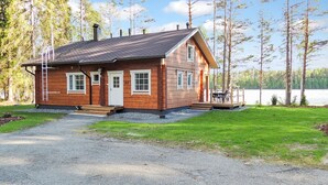 A wooden cabin with a gravel driveway, a front porch, and a lake view. - Nesterin helmi by Interhome (Eno)