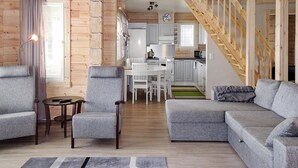 A modern living room with a grey sofa, armchairs, and a coffee table. A staircase leads to an upper level. - Nesterin helmi by Interhome (Eno)