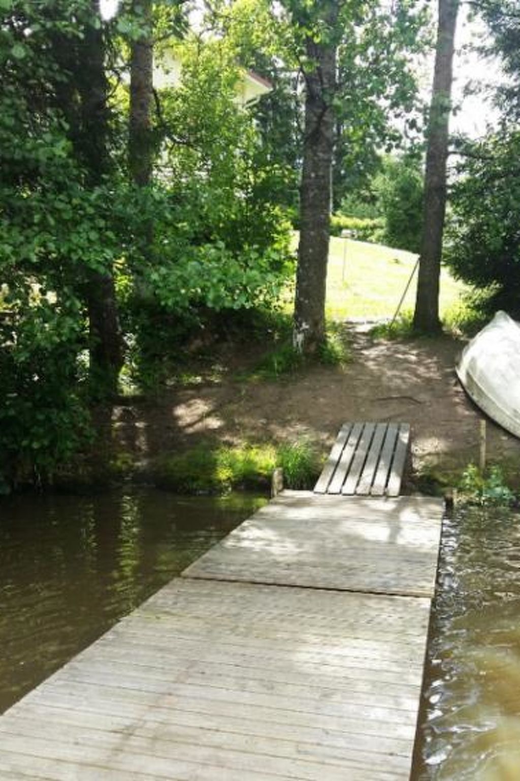 Un muelle de madera se adentra en un cuerpo de agua, rodeado de exuberante vegetación y árboles.