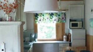 A kitchen with wooden cabinets, a microwave, and a window with a view of greenery.