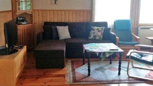A cozy living room with a wooden floor, a sofa, a small table, and a television.