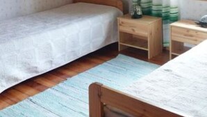 A small, cozy room with a single bed, a nightstand, and a window with curtains.