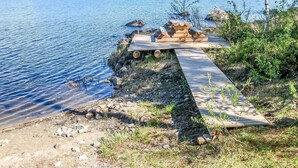 Un muelle de madera que se extiende hacia un lago tranquilo, rodeado de rocas y vegetación escasa.