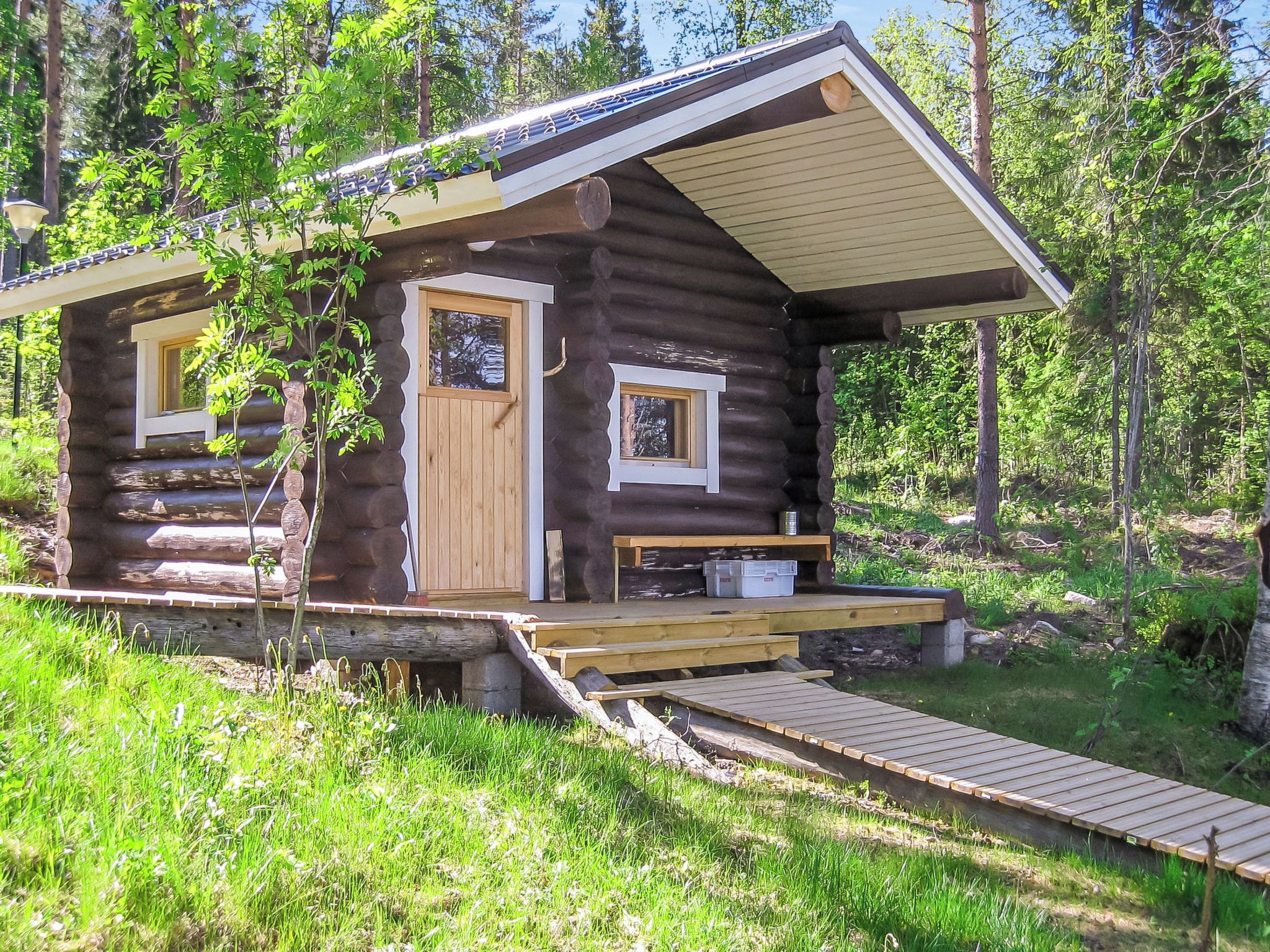 A log cabin with a wooden deck, a front door, and a small porch area.