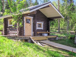 Eine Blockhütte mit einer Holzterrasse, einer Haustür und einer kleinen Veranda.