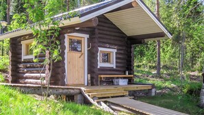 Una cabaña de troncos con una terraza de madera y un pequeño porche.