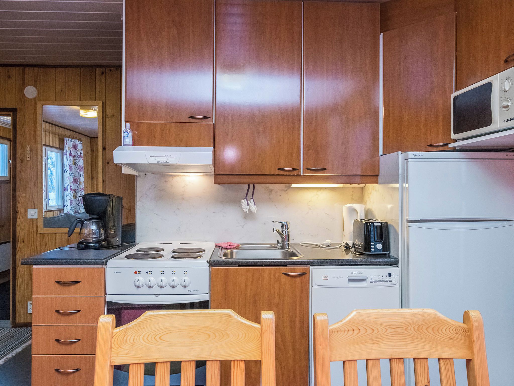 A compact kitchen with wooden cabinets, a stove, a sink, and a microwave.