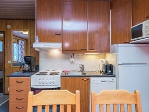 Una cocina compacta con armarios de madera, estufa, lavamanos y microondas.