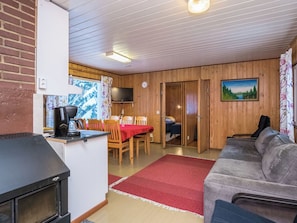 A cozy cabin interior with a dining area, a sofa, and a kitchen with a stove.