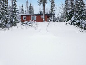 Une cabane rouge entourée d’arbres couverts de neige.